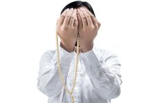 1643199 مرد مسلمان آسیایی در حال دعا با مهره های نماز بر روی دست هایش جدا شده روی پس زمینه سفید